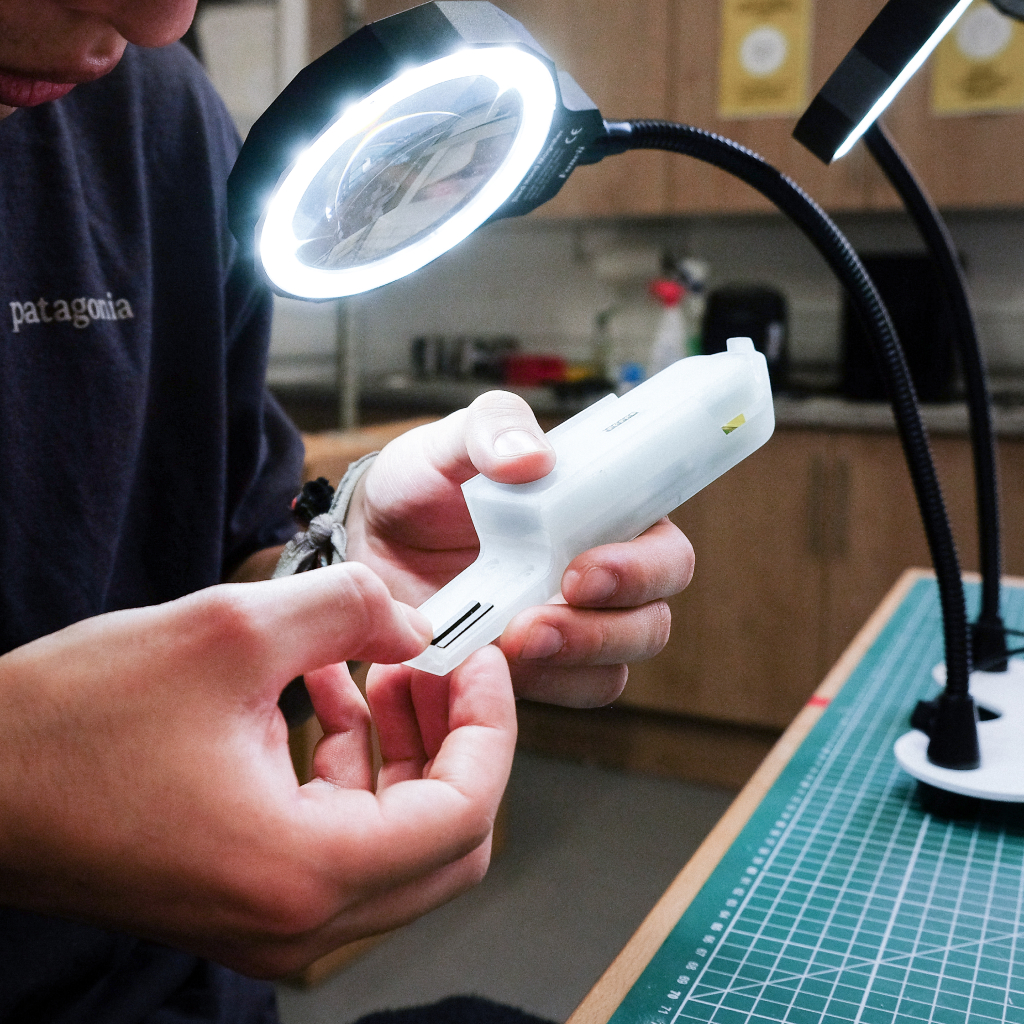 Engineer inspecting a Butterfly device under a magnifying lamp